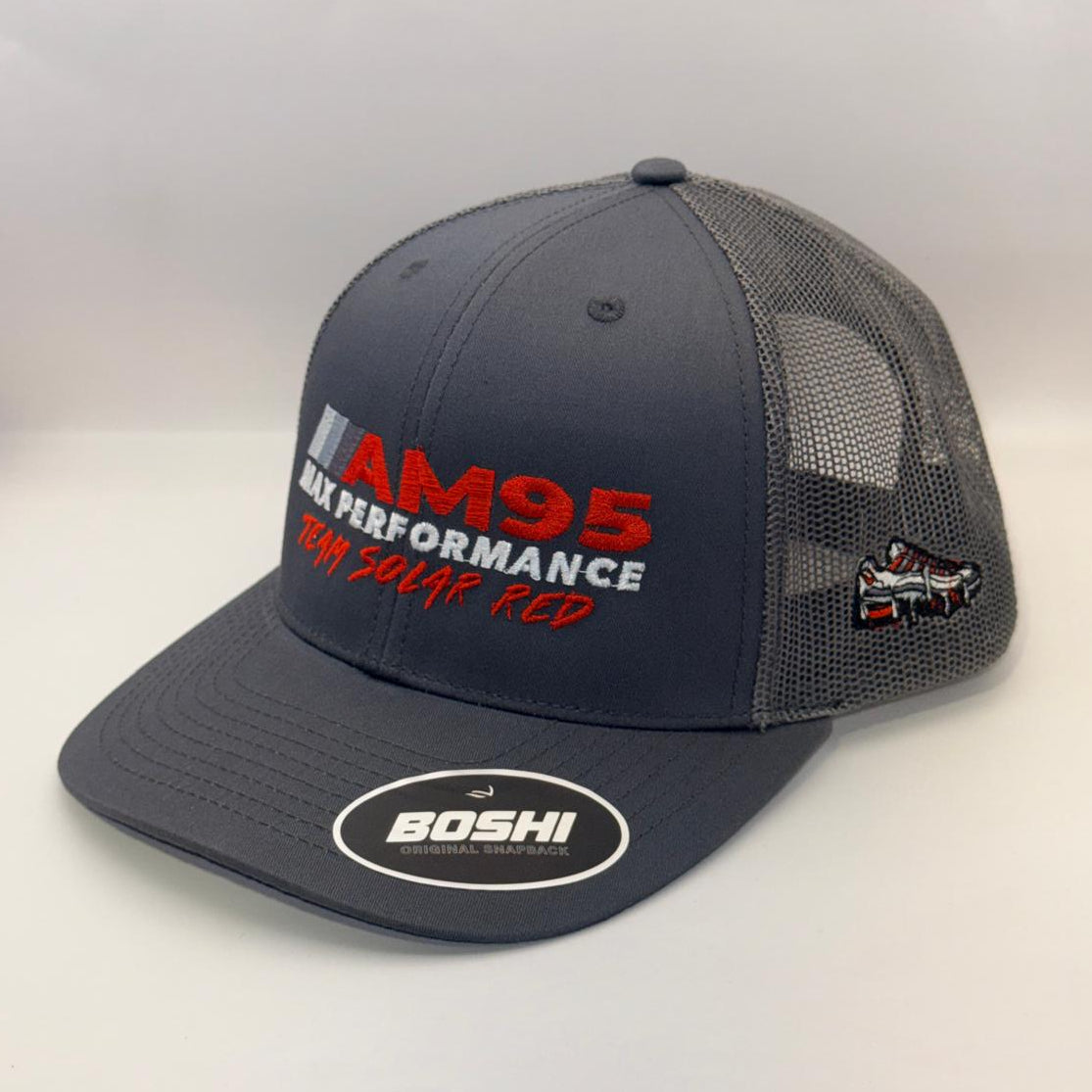 A dark gray and black mesh-back trucker hat with 'AM95 RAIN PERFORMANCE' printed on the front in red and white, featuring a circular 'BOSHI' sticker on the brim and a small side patch.